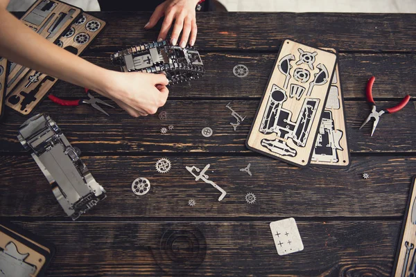 Vista superior de manos femeninas construyendo mecanismo de metal —  Fotos de Stock