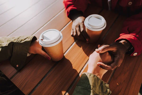 Detailní záběr ze dvou lidí, drželi se za ruce a pití kávy — Stock fotografie