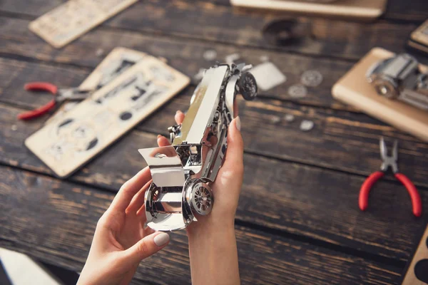 Laconieke afbeelding van metalen speelgoedauto in de handen van de jonge dame — Stockfoto