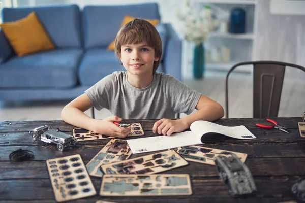 Menino calmo sorrindo enquanto mostra seu hobby em casa — Fotografia de Stock