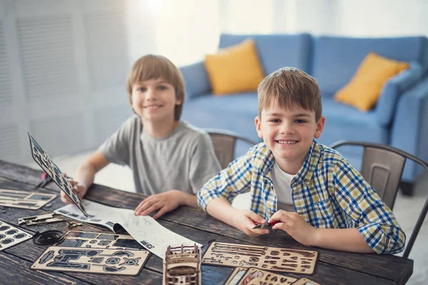 Two boys smiling and looking happy while enjoying creating wooden models