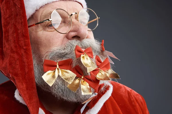 Santa Claus with bows in beard posing on gray background — Stock Photo, Image