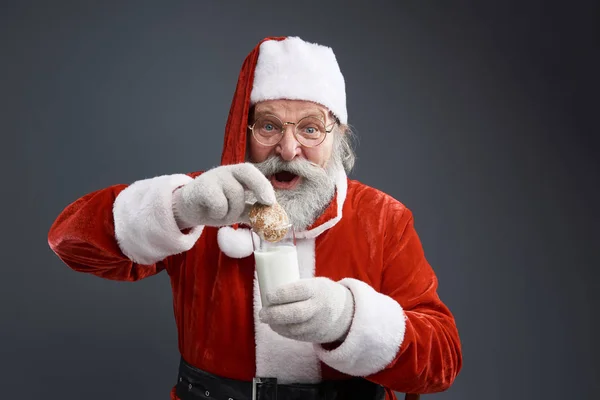 Santa Claus v brýlích namáčení cookie v mléce — Stock fotografie