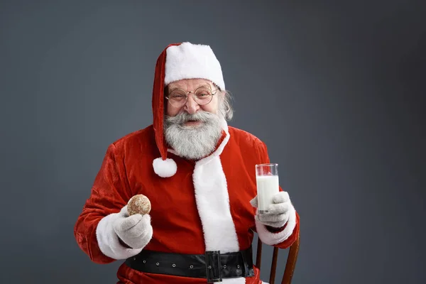 Smiling Santa Claus with cookie and milk posing on gray background — Stock Photo, Image