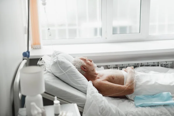 Alter Mann liegt im Bett und wird intravenös behandelt — Stockfoto