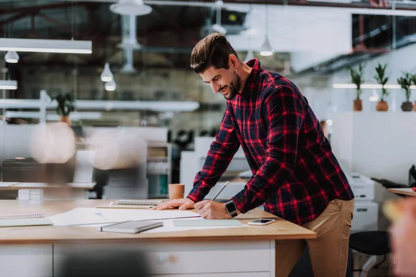 Fröhlicher, bärtiger Ingenieur, der im Büro einen Drahtseilakt macht — Stockfoto