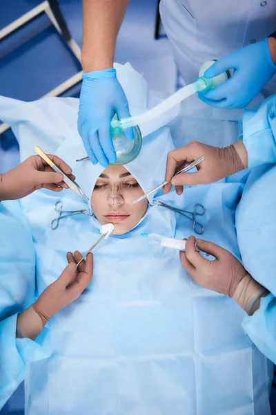 Medici professionisti in piedi vicino al paziente durante la chirurgia plastica — Foto Stock