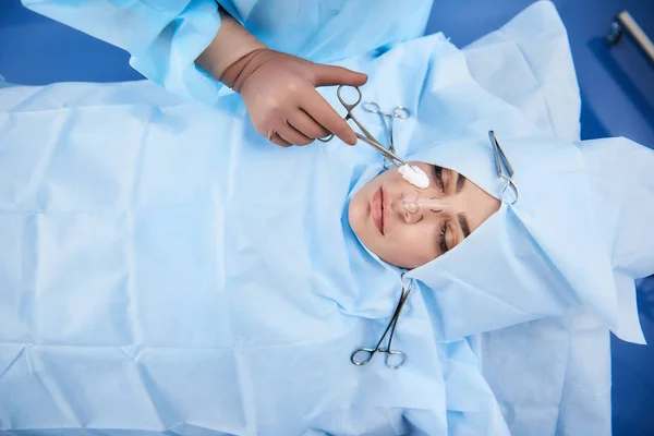Vista superior da jovem na mesa de operação com linhas no nariz — Fotografia de Stock
