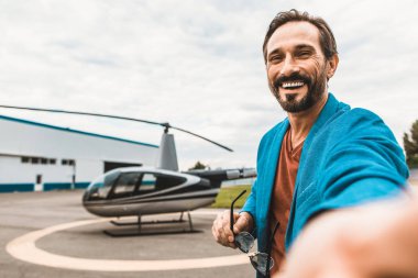 Mutlu adam helikopter önünde ayakta duygusal selfie