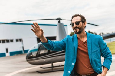 Mutlu adam yanında helikopter olurken elini sallayarak