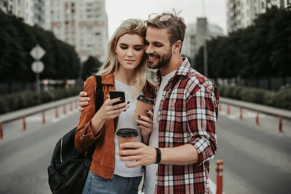 Dos alegres usando un teléfono inteligente moderno en la calle — Foto de Stock