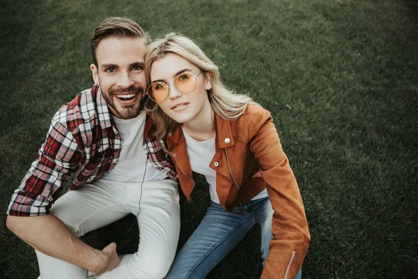 Feliz pareja joven sentada sobre hierba verde —  Fotos de Stock