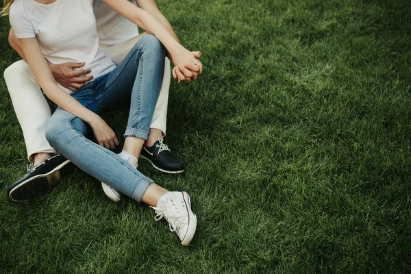 Tender acting couple locating on green grass — Stock Photo, Image