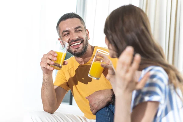 Felice coppia sta ridendo e bevendo succo d'arancia — Foto Stock