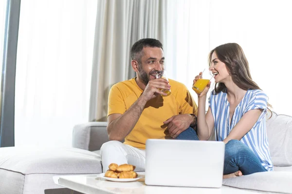 Ridendo marito e moglie stanno bevendo succo d'arancia — Foto Stock