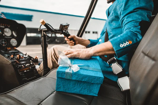 Hombre cuidadoso tocando el presente mientras está sentado en la cabina del helicóptero — Foto de Stock