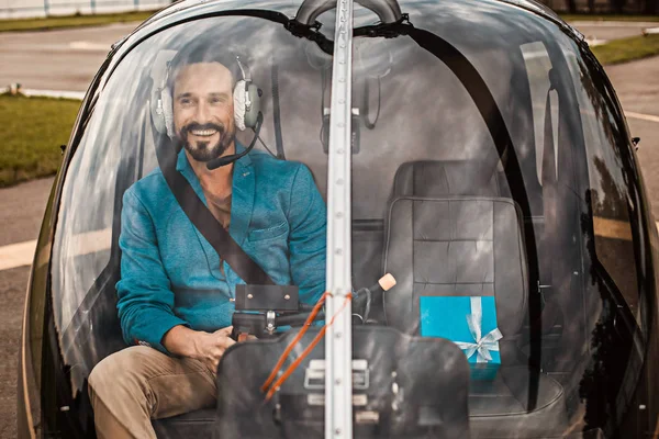 Счастливый человек улыбается, сидя в кабине вертолета со своим подарком — стоковое фото