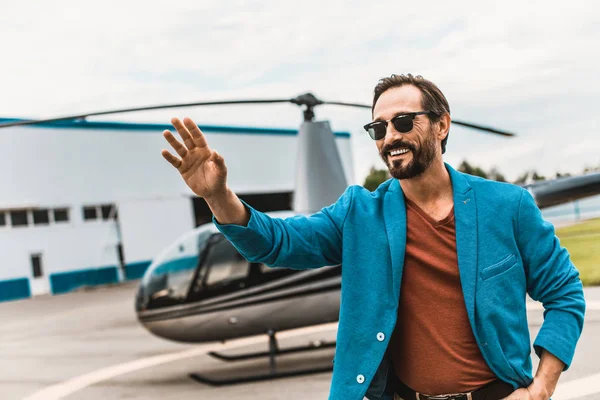 Feliz hombre agitando su mano mientras está al lado del helicóptero — Foto de Stock