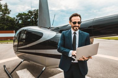 Mutlu işadamı duran helikopter yakınındaki modern dizüstü koşullarının