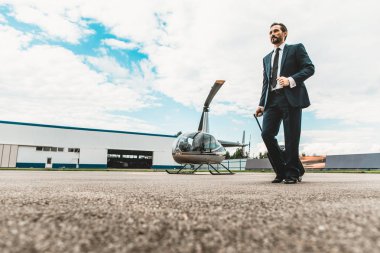 Çantayı helikopter platformu üzerinde taşıyan ciddi sakallı adam