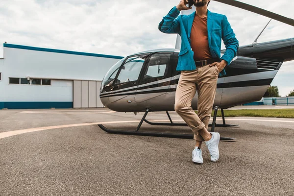 Hombre relajado hablando por teléfono y de pie cerca del helicóptero — Foto de Stock