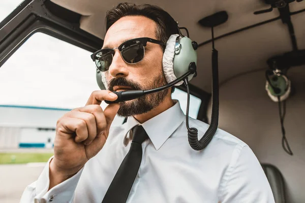 Jistý pilot nosí sluneční brýle, zatímco sedí v kabině — Stock fotografie