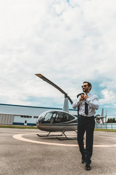 Hombre de negocios tranquilo caminando en la plataforma del helicóptero y sonriendo — Foto de Stock