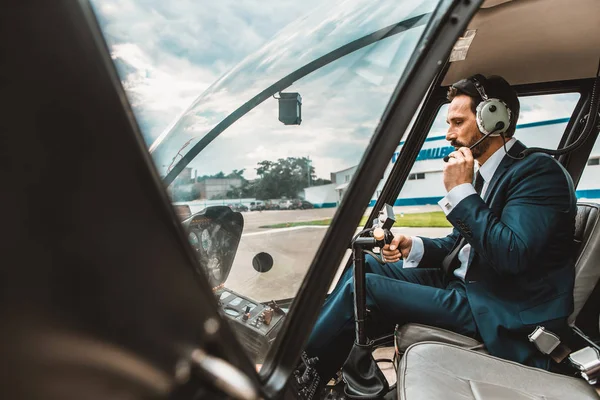 Tranquilo hombre comprobar la conexión mientras está sentado en la cabina del helicóptero — Foto de Stock