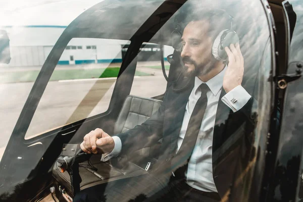 Calm man wearing headphone while sitting in the helicopter