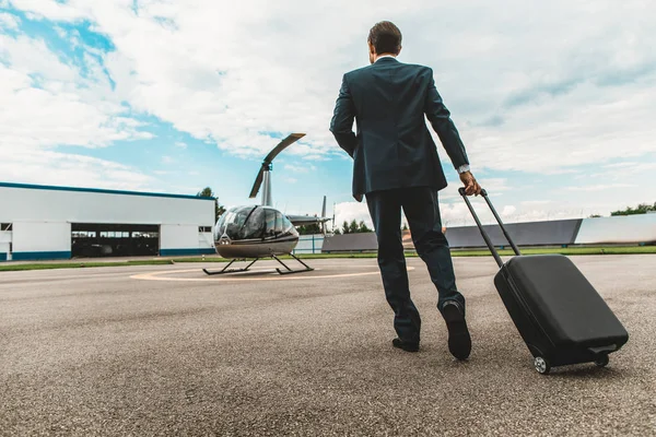 Elegante hombre de negocios llevando su maleta y caminando hasta el helicóptero — Foto de Stock