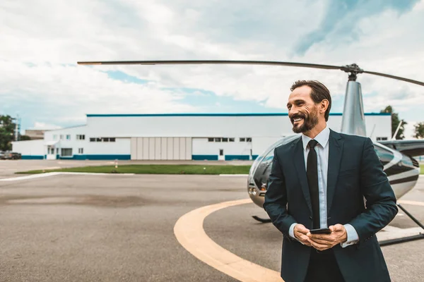 Hombre guapo sonriendo mientras está de pie en la plataforma del helicóptero — Foto de Stock