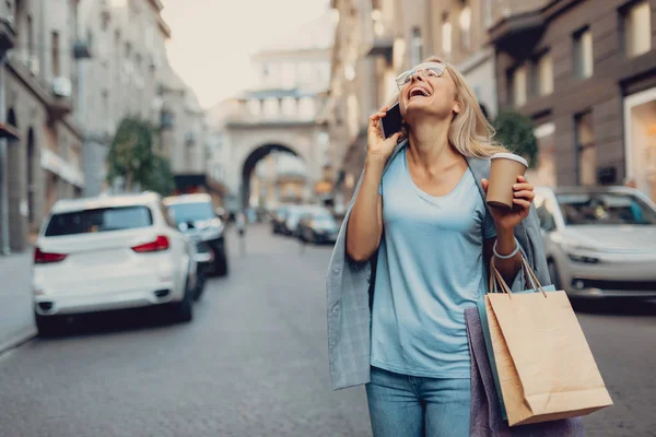 Encantadora mujer con bebida caliente hablando por celular y riendo — Foto de Stock