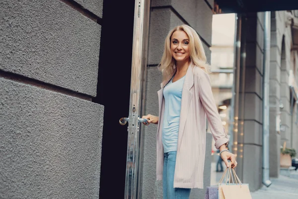 Красивая блондинка открывает дверь магазина одежды — стоковое фото