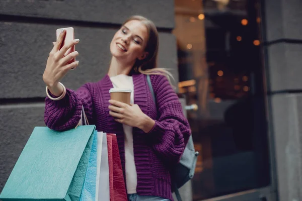 Mujer joven con bebida caliente haciendo selfie en la calle — Foto de Stock