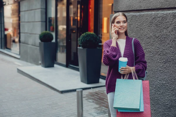 Mooie jonge vrouw met warme dranken, praten op mobiele telefoon — Stockfoto