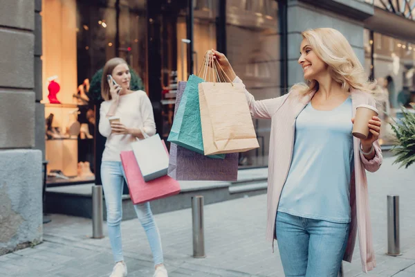 Encantadora dama mirando bolsas de compras mientras su hija habla por teléfono celular — Foto de Stock