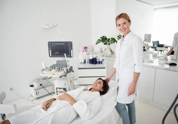 Cosmetologist σε λευκή εργαστήριο παλτό στέκεται κοντά Νεαρη κυρία — Φωτογραφία Αρχείου
