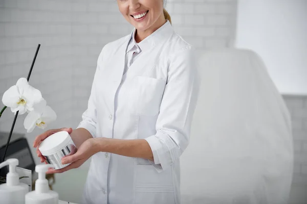 Esteticista alegre demonstrando produto de cuidados com a pele eficaz — Fotografia de Stock