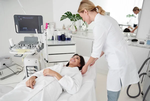 Cosmetólogo amigable cuidando de la joven en el salón de belleza — Foto de Stock