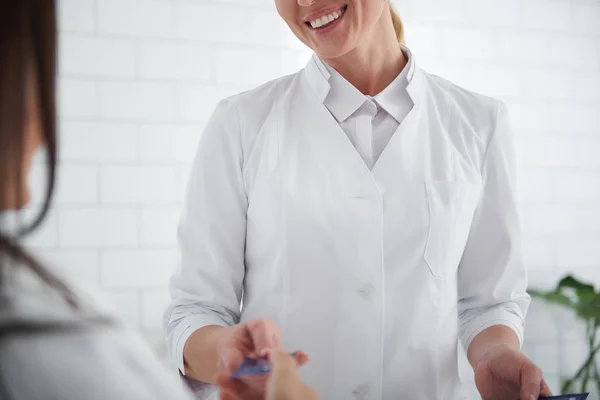 Esteticista dando muestras de crema cosmética a la joven dama — Foto de Stock