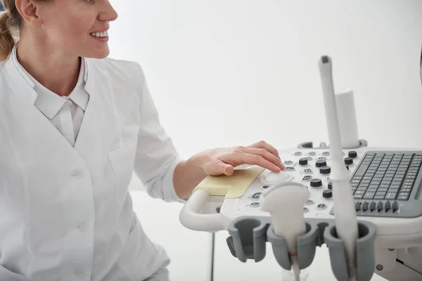 Молодий лікар використовує ультразвуковий сканер і посміхається — стокове фото