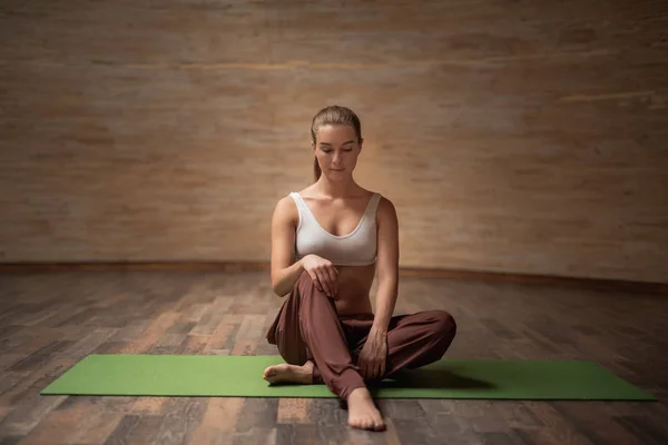 Comprimento total de jovem senhora fechando os olhos enquanto sentada no tapete de ioga — Fotografia de Stock