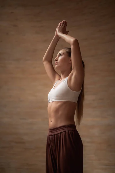 Ruhige junge Frau legt Hände über den Kopf, während sie Yoga praktiziert — Stockfoto
