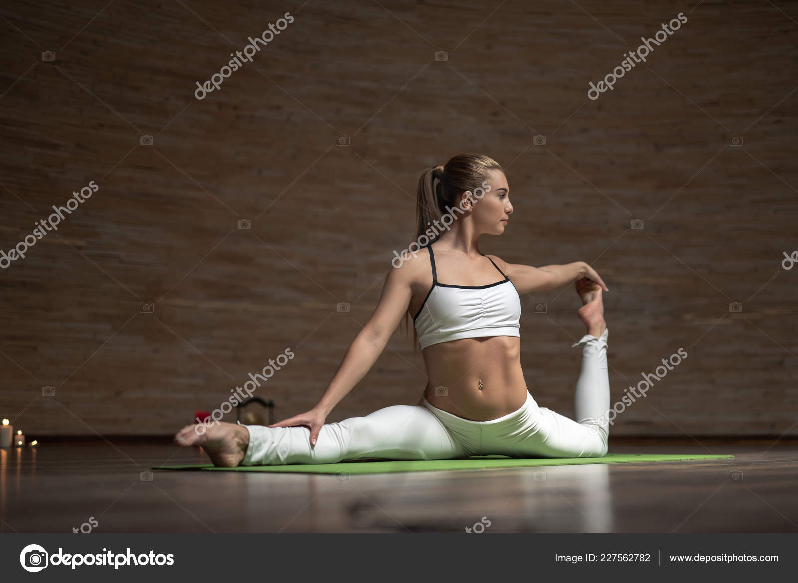 Slim lady touching her toes while stretching her legs on yoga mat
