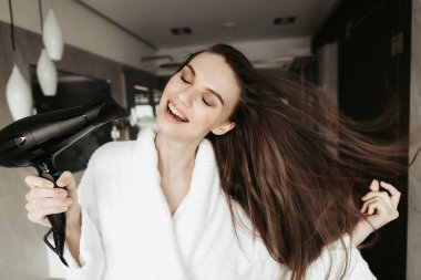 Genç kadın kurutma saç blowdryer ile gülümseyen