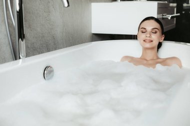 Rahatlatıcı baloncuk banyo genç gülümseyen kadın