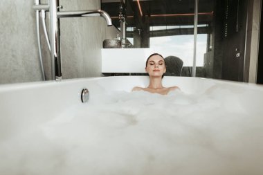 Rahatlatıcı baloncuk banyo genç gülümseyen kadın