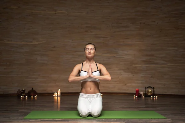 Senhora calma sentada de joelhos e meditando com os olhos fechados — Fotografia de Stock