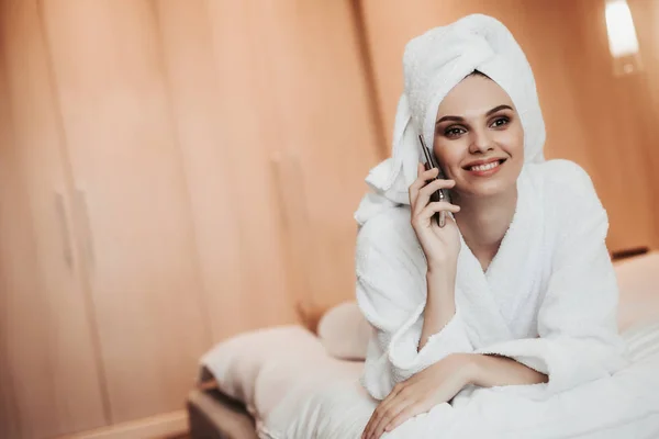 Jovem mulher de roupão falando por telefone na cama — Fotografia de Stock