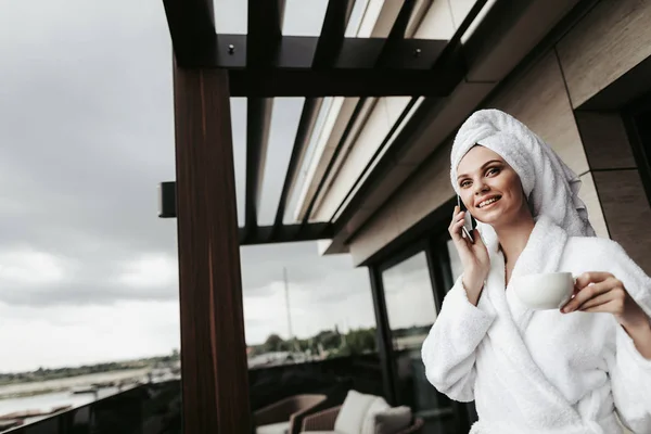 Молодая женщина в халате разговаривает по телефону — стоковое фото